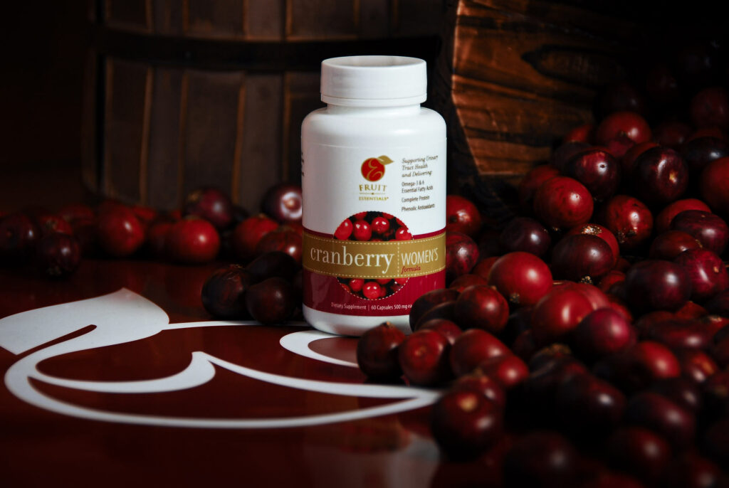 Bottle of supplement product photography in a still life scene with cranberries and company logos