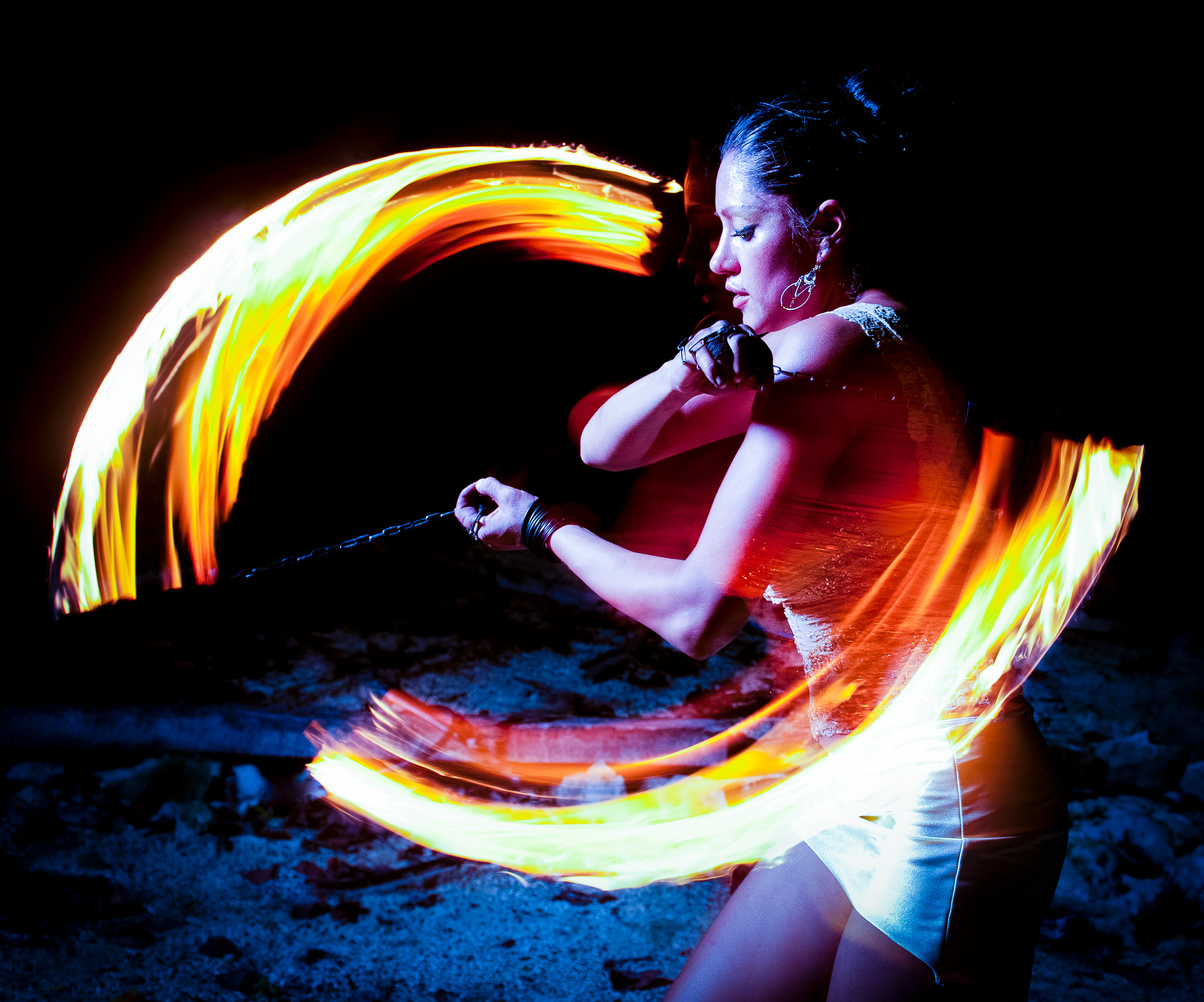 Female firedancer - woman fire spinning with fire poi chains