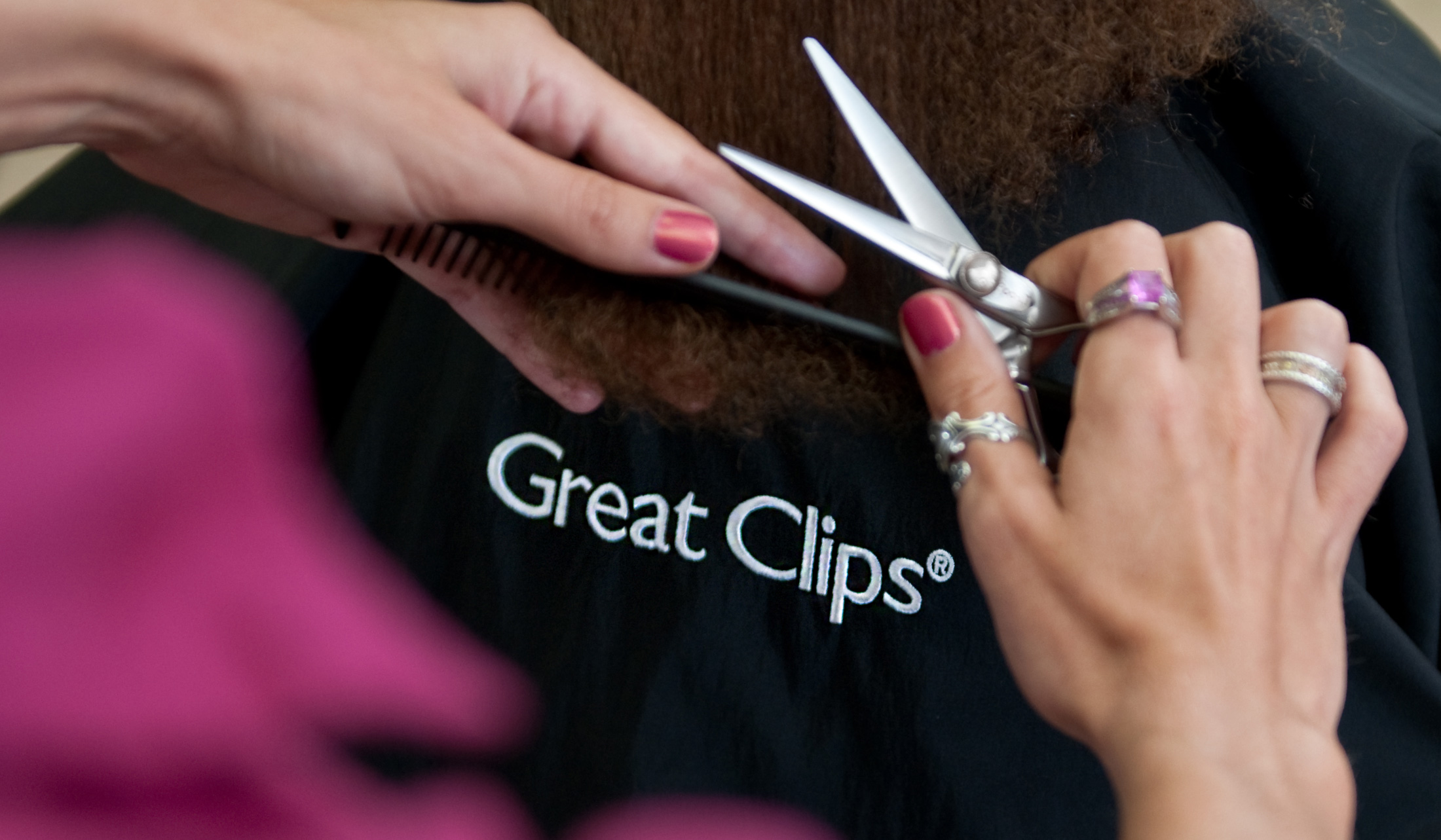 Over the shoulder photo of a Great Clips logo through the hands of a stylist