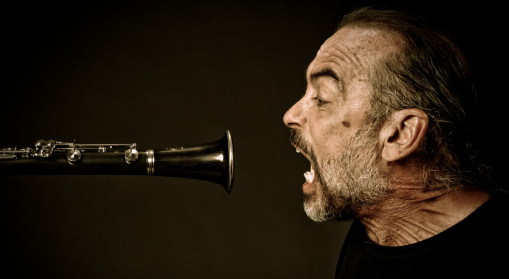 A classical musician portrait that is unique showing a man screaming into a oboe
